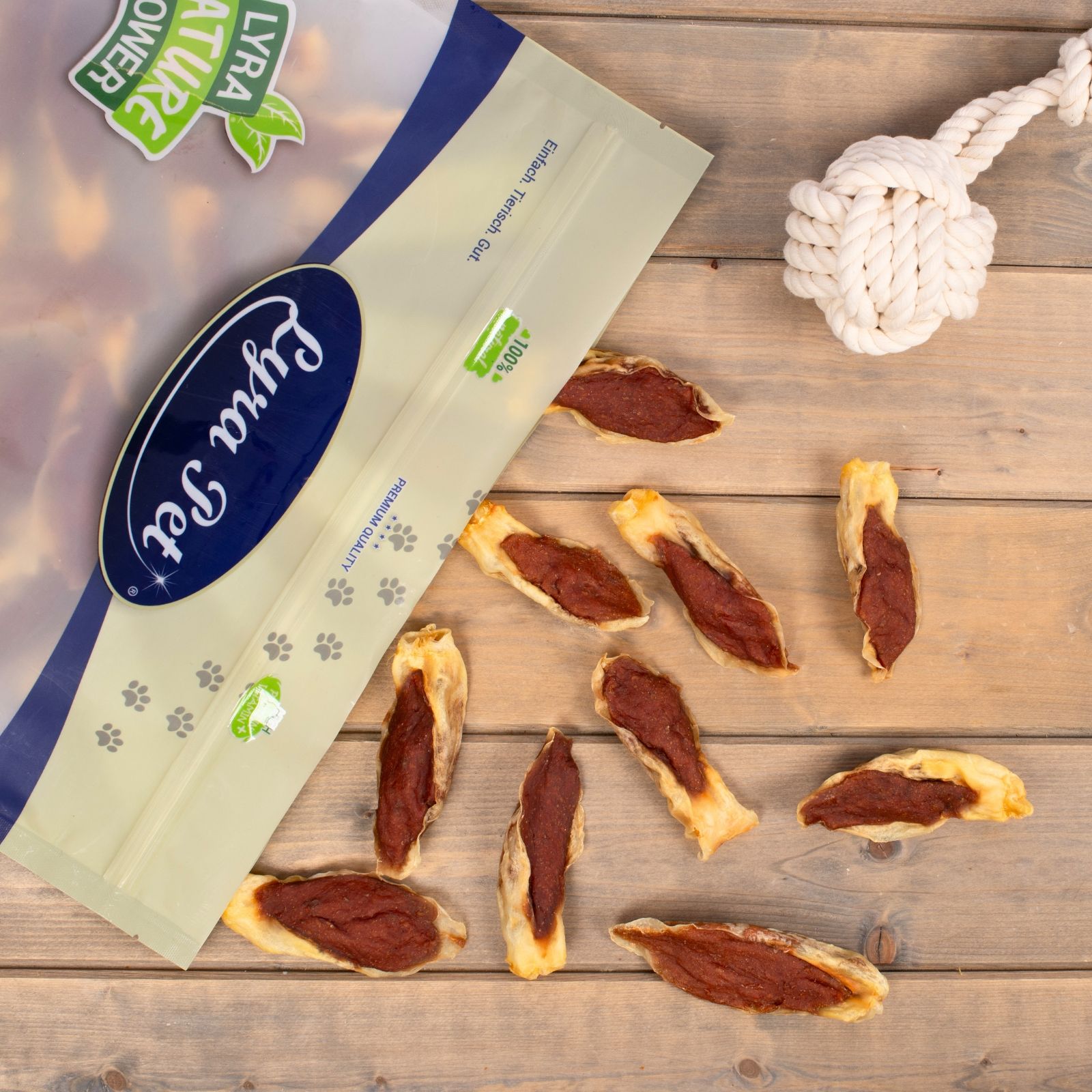 Lyra Pet Hundeleckerli-Beutel mit verstreuten Leckerlis auf Holzboden.