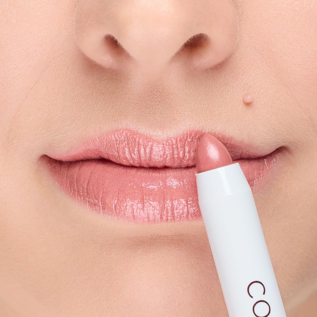 Lippenstift in Rosa, wird auf Lippen aufgetragen. Der Lippenstift ist in einem weißen Stiftgehäuse.