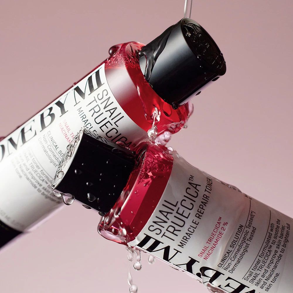 Zwei Flaschen SOME BY MI Snail TrueCICA Miracle Repair Toner, rot und mit schwarzem Deckel, mit Wassertropfen.