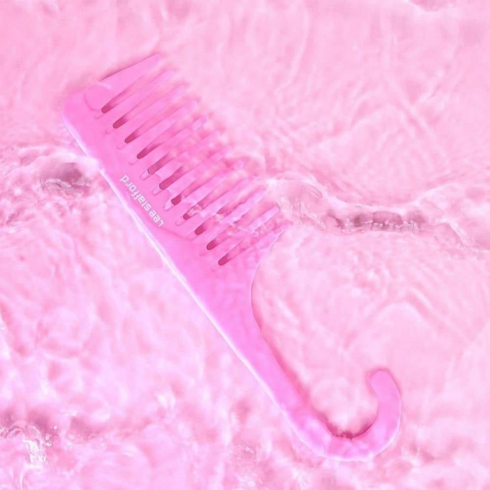 Ein rosafarbener Kamm mit breiten Zinken schwimmt in leicht bewegtem Wasser.