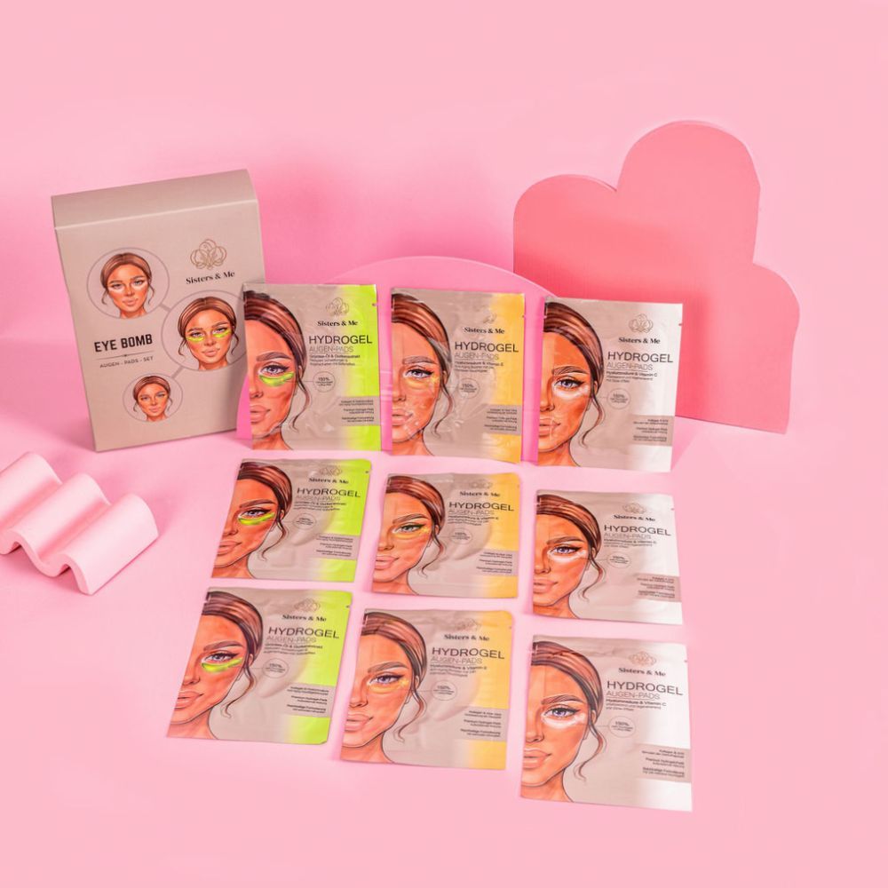 Produktverpackung mit Augenpatches und Einzelverpackungen. Aufschrift: EYE BOMB, Hydrogel. Logo: Sisters & Me. Rosa Hintergrund.