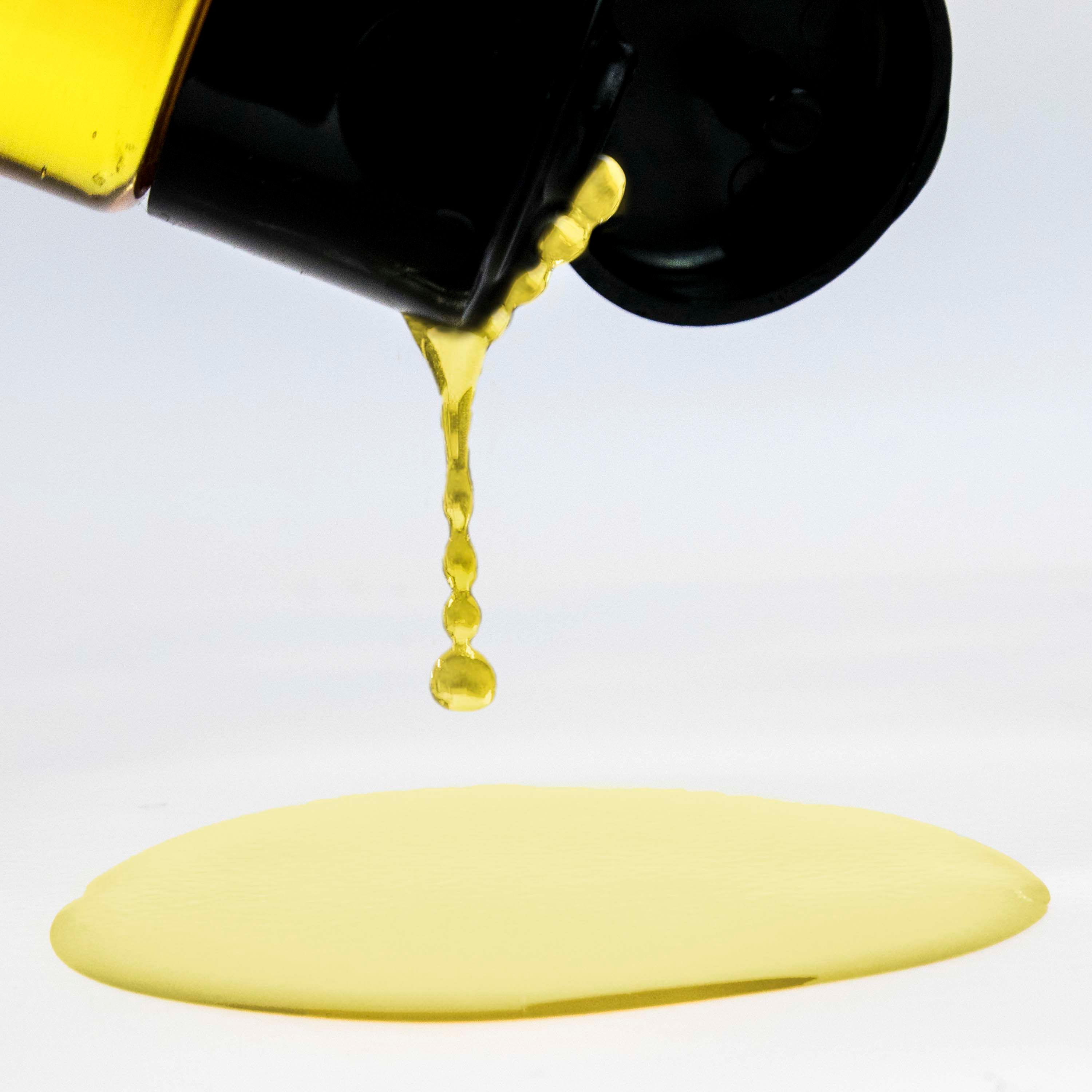 Gelbe Flüssigkeit tropft aus dem Flaschenhals. Auf weißem Hintergrund.