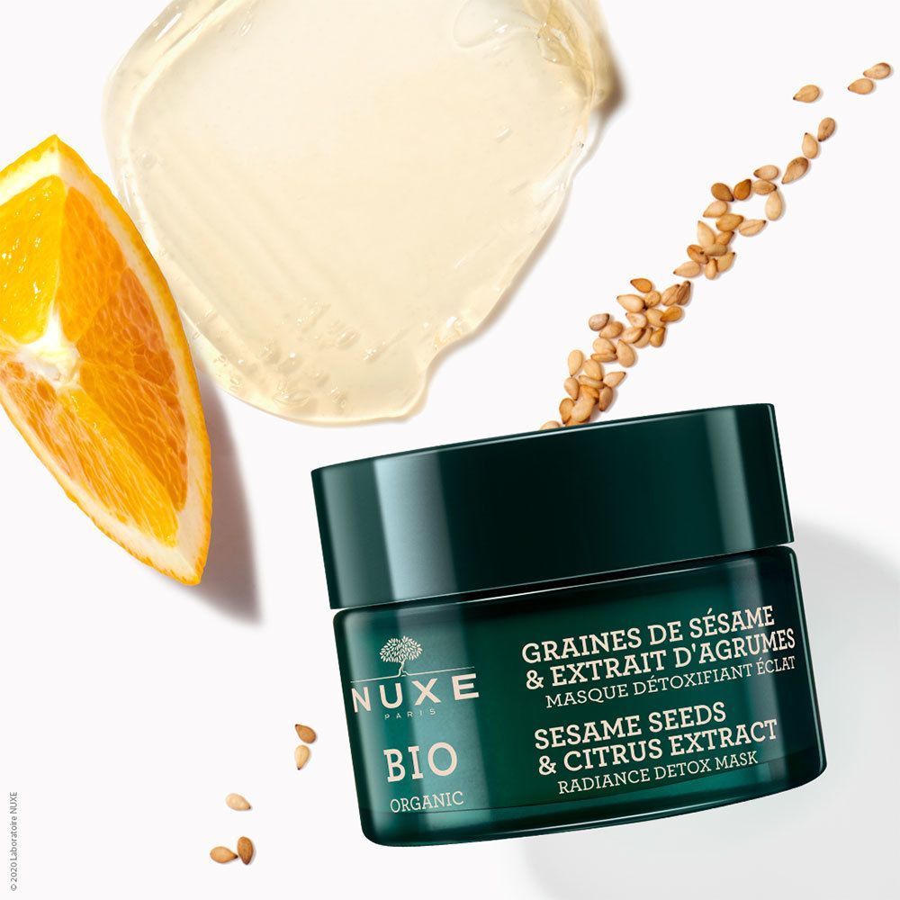 NUXE BIO-Gesichtsmaske mit Zutaten: Orangenscheibe, Sesamkörner und Maskenprobe. Text: GRAINES DE SÉSAME & EXTRAIT D'AGRUMES, MASQUE DÉTOXIFIANT ÉCLAT, RADIANCE DETOX MASK.