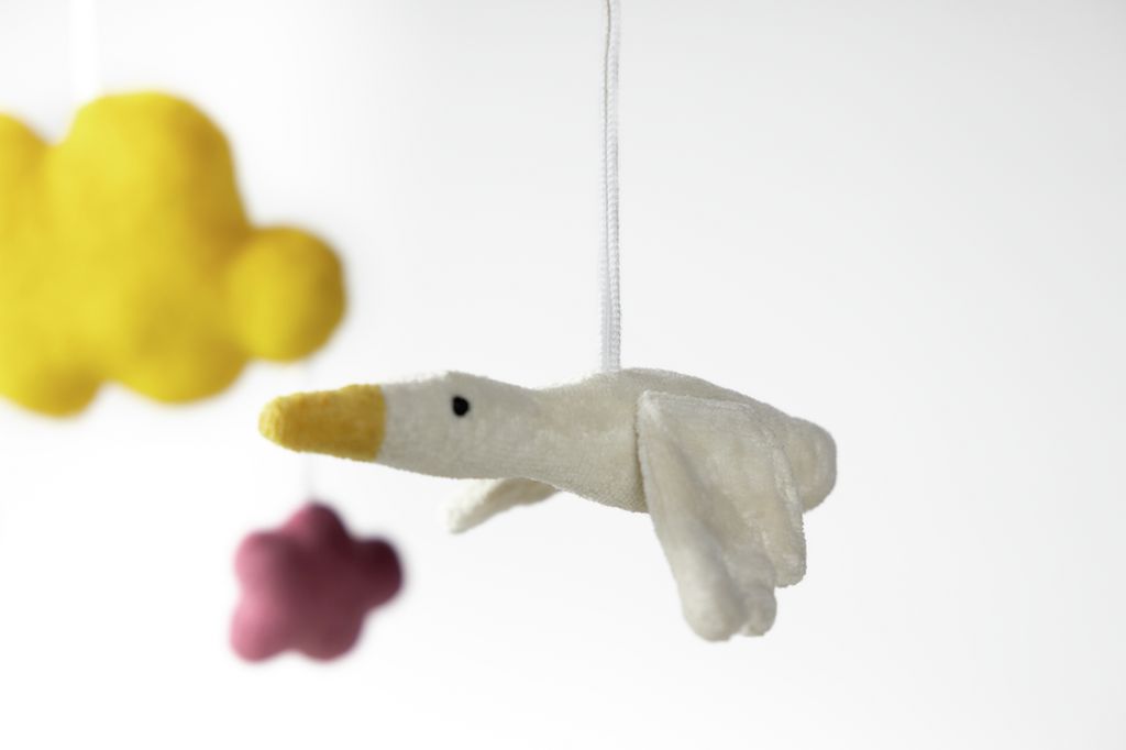 Nahaufnahme einer weißen Gans mit gelbem Schnabel und Flügeln. Gelbe Wolke und rosa Wolke im Hintergrund.