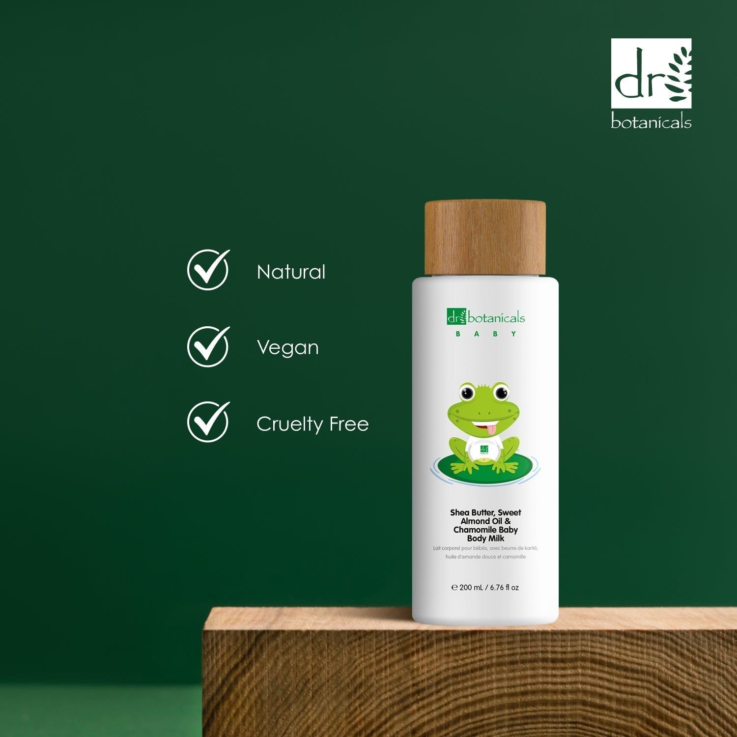 Produktflasche mit Holzdeckel. Text: 'Natural', 'Vegan', 'Cruelty Free'. Marke: Dr Botanicals Baby. Hintergrund: Holzblock, grün.