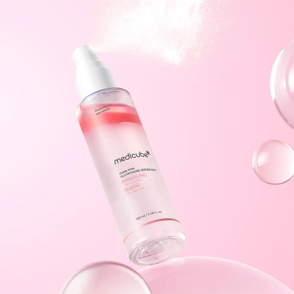 Medicube PDRN Pink Glutathione Serum Mist Flasche sprüht Nebel. Schwebende Glaskugeln und rosa Hintergrund.