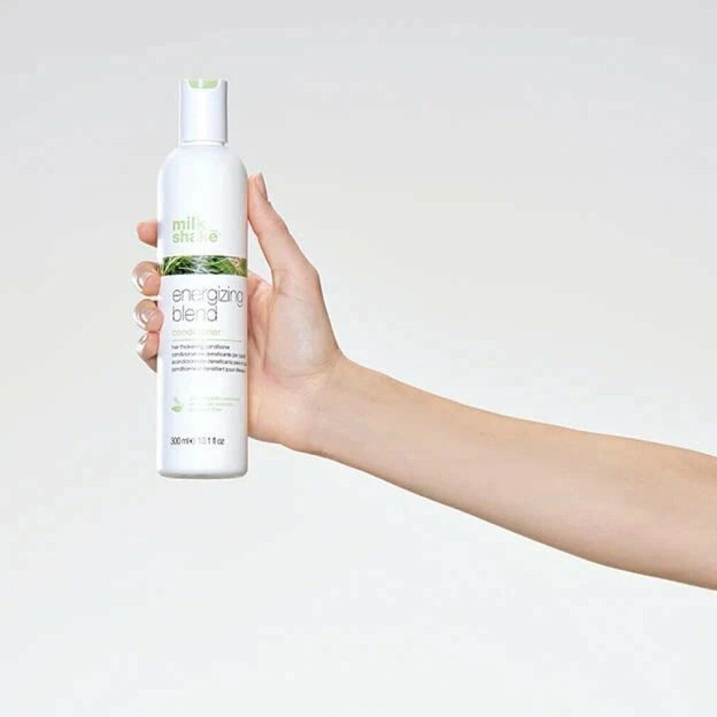 Weiße Flasche mit grünem Etikett, gehalten von einer Hand. Aufschrift: milk_shake, Energizing Blend Conditioner. 300 ml.