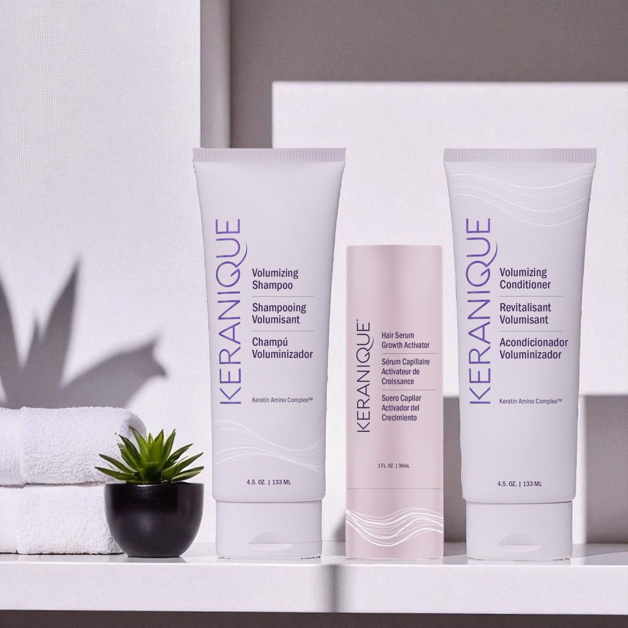 Keranique Shampoo, Conditioner und Serum. Auf einem Regal. Weiße Flaschen mit lila Etiketten.