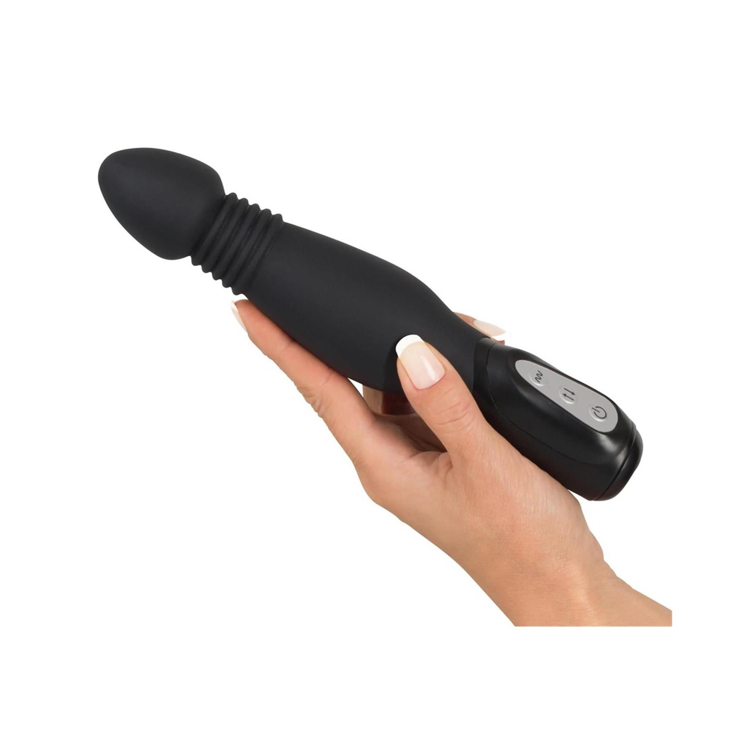 Schwarzer Vibrator mit konischem Kopf und geriffelter Textur. Bedienfeld mit zwei Knöpfen. In einer Hand gehalten.