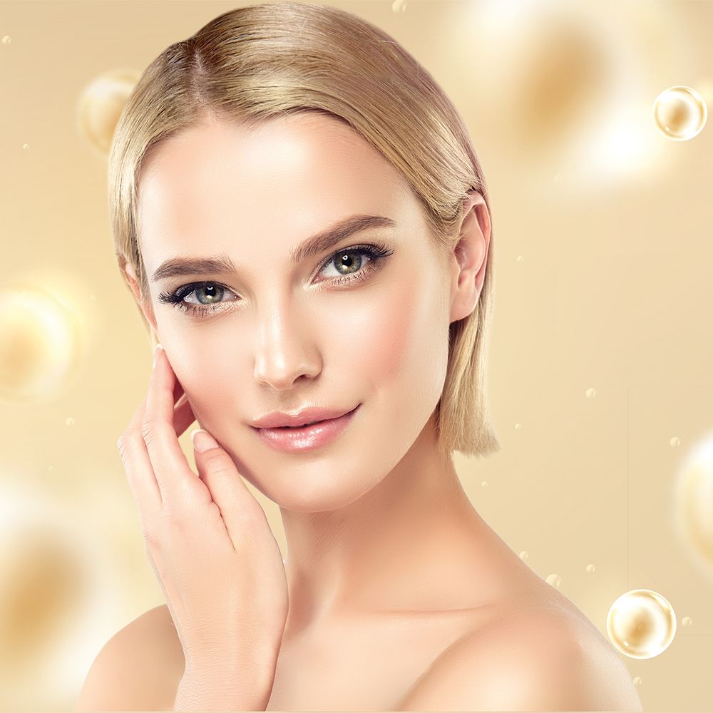 Porträt einer Frau mit heller Haut. Sie berührt ihr Gesicht. Goldene Kugeln im Hintergrund.