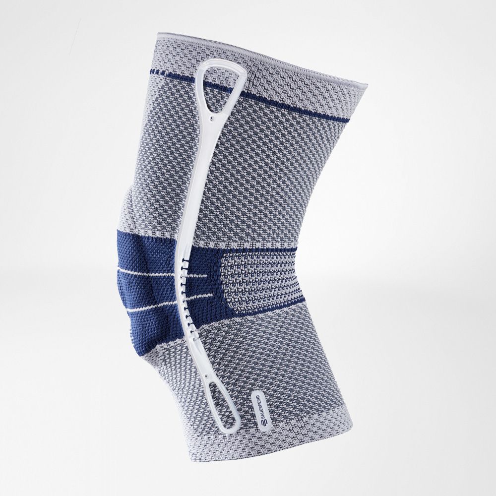 Kniebandage, grau-blaues Gewebe, mit blauem Verstärkungsbereich. Weißes Hilfsmittel zur Handhabung.