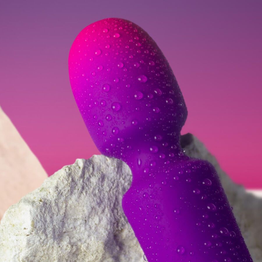 Lila Vibrator mit Wassertropfen. Farbverlauf von Lila zu Pink. Auf einem Stein platziert.