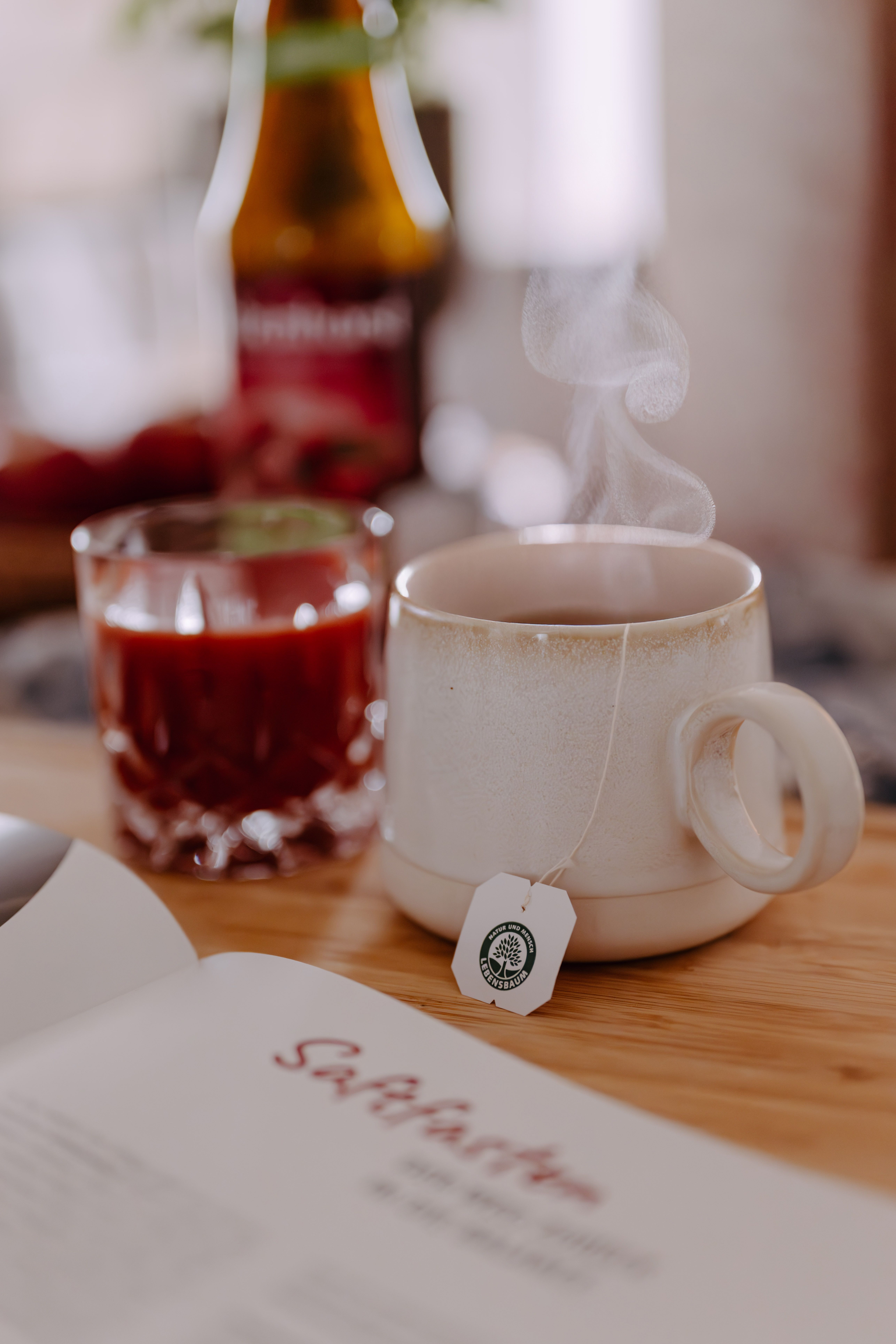 Glas Saft, Tasse Tee, Broschüre auf Holzbrett. Dampf aus der Tasse. Teebeutel-Etikett.