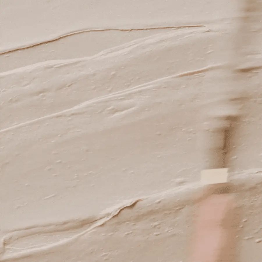 Nahaufnahme von cremefarbener Textur. Die Textur ist glatt und leicht glänzend.