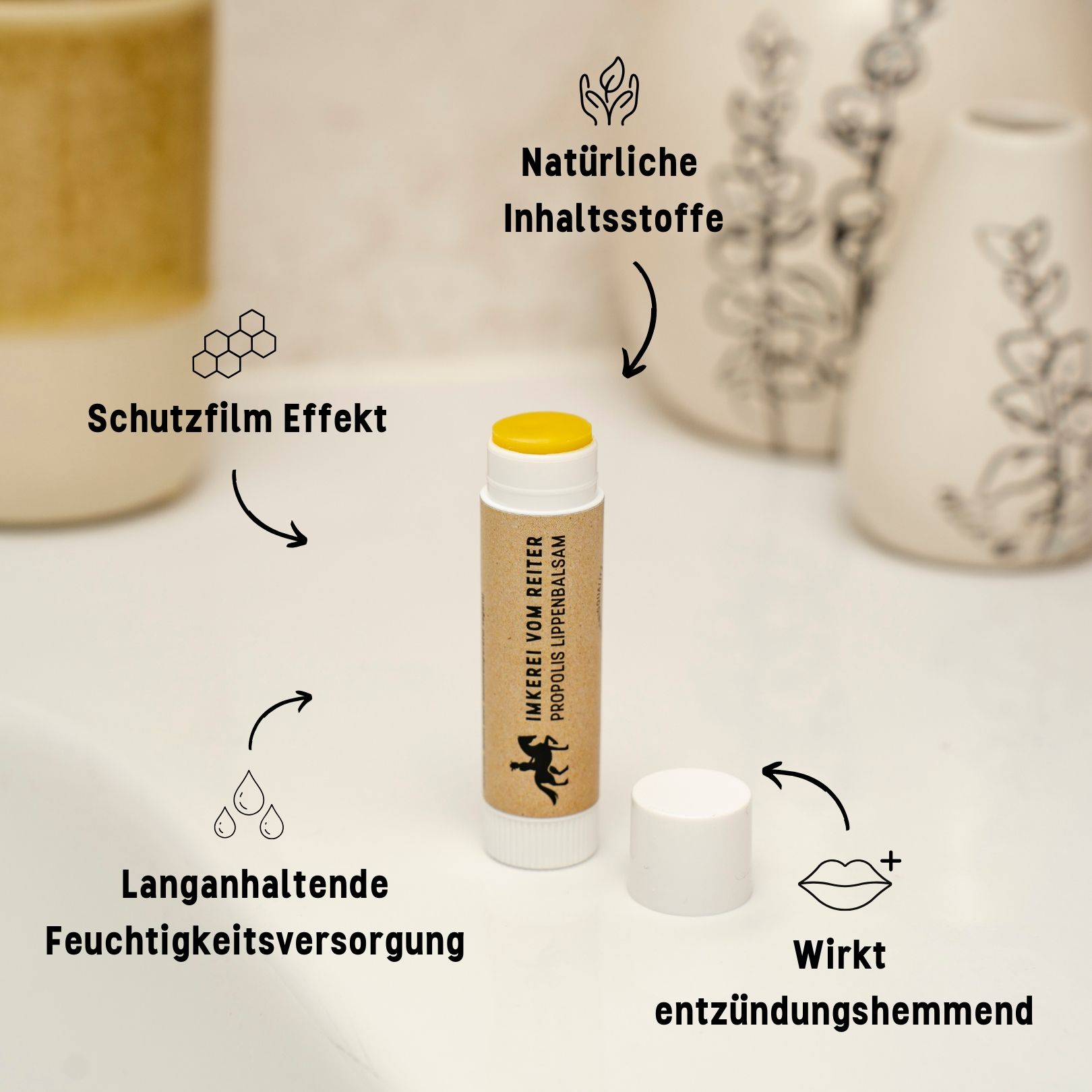 Lippenbalsam-Stift mit weißem Deckel. Pfeile zeigen auf: Schutzfilm, langanhaltende Feuchtigkeitsversorgung, wirkt entzündungshemmend, natürliche Inhaltsstoffe.