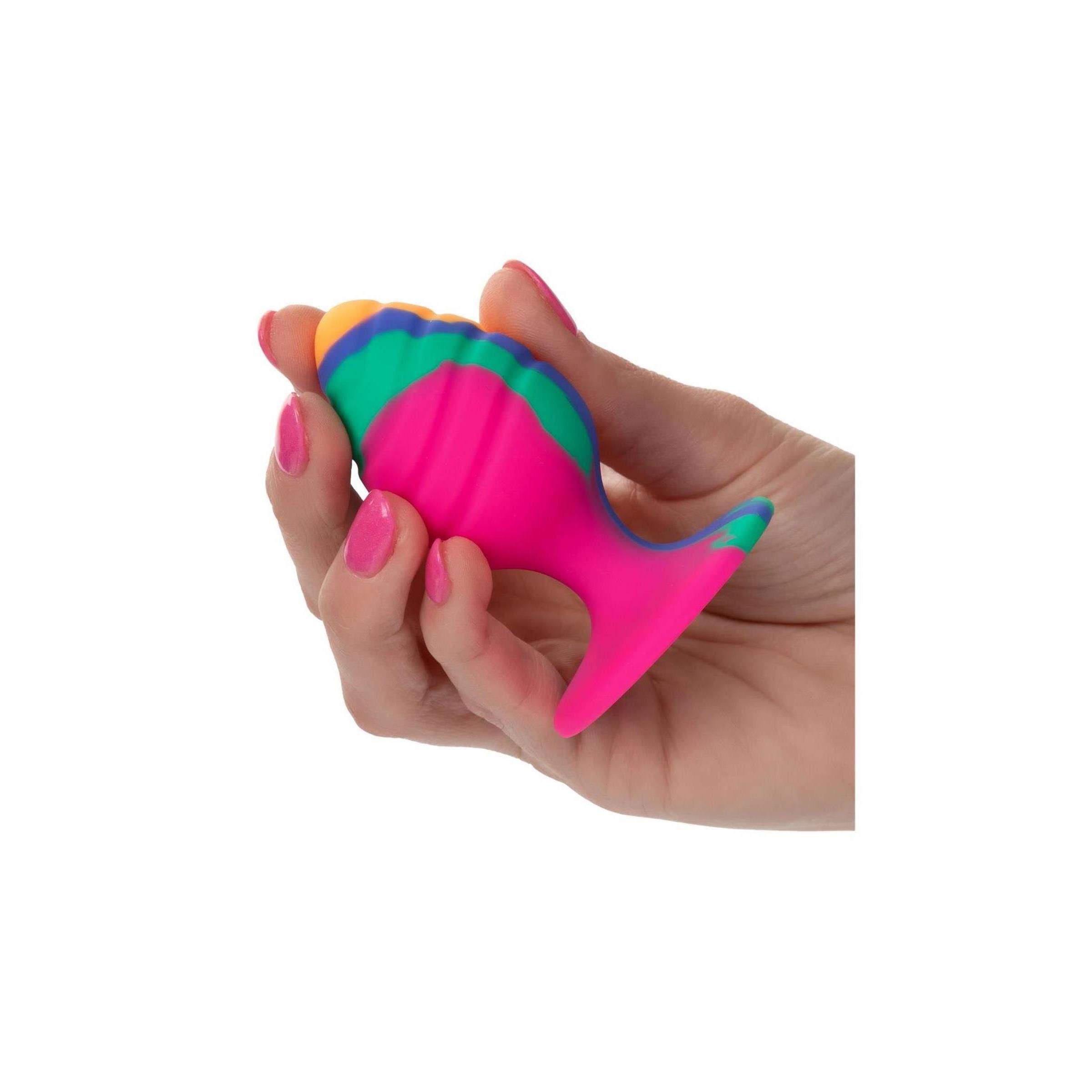 Mehrfarbiger Analplug in einer Hand gehalten. Der Plug hat eine konische Form mit einem breiten, flachen Sockel.