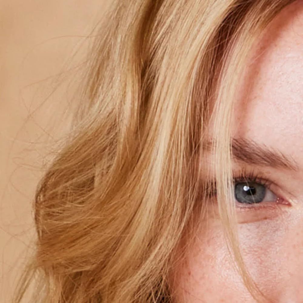 Ausschnitt eines Gesichts mit blondem Haar und blauem Auge. Haare fallen über die Stirn. Haut mit Sommersprossen.