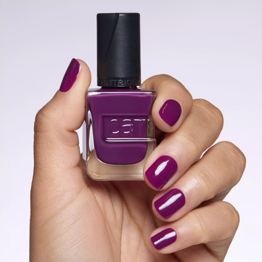 Hand mit lackierten Nägeln in dunklem Violett. Nagellackflasche daneben. Catrice-Logo sichtbar.