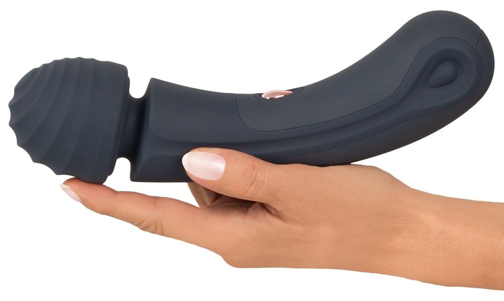 Dunkelgrauer Vibrator in Hand gehalten. Geriffelter Kopf, geschwungener Griff. Rosa Knopf. Silikon-Material.