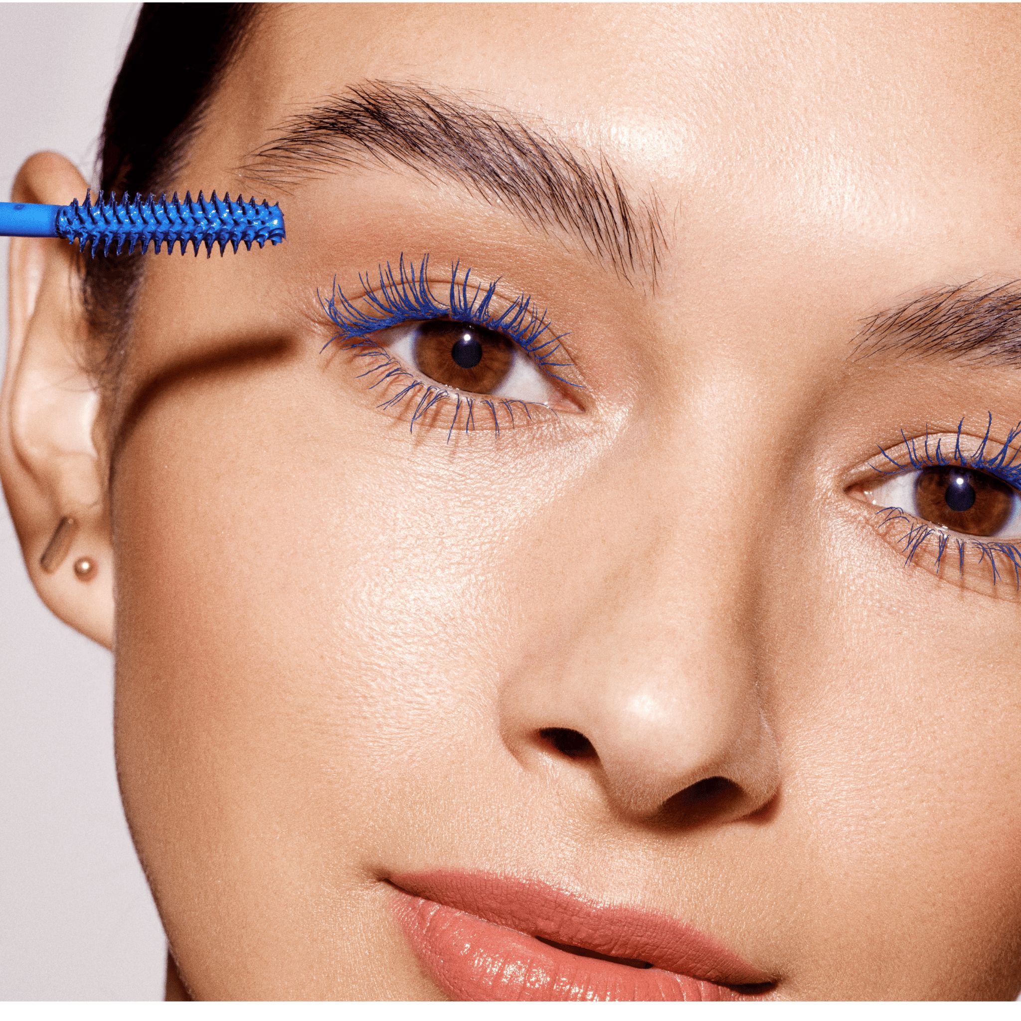 Frau trägt blauen Mascara mit der blauen Bürste des Double-Ended Volume Sets auf.