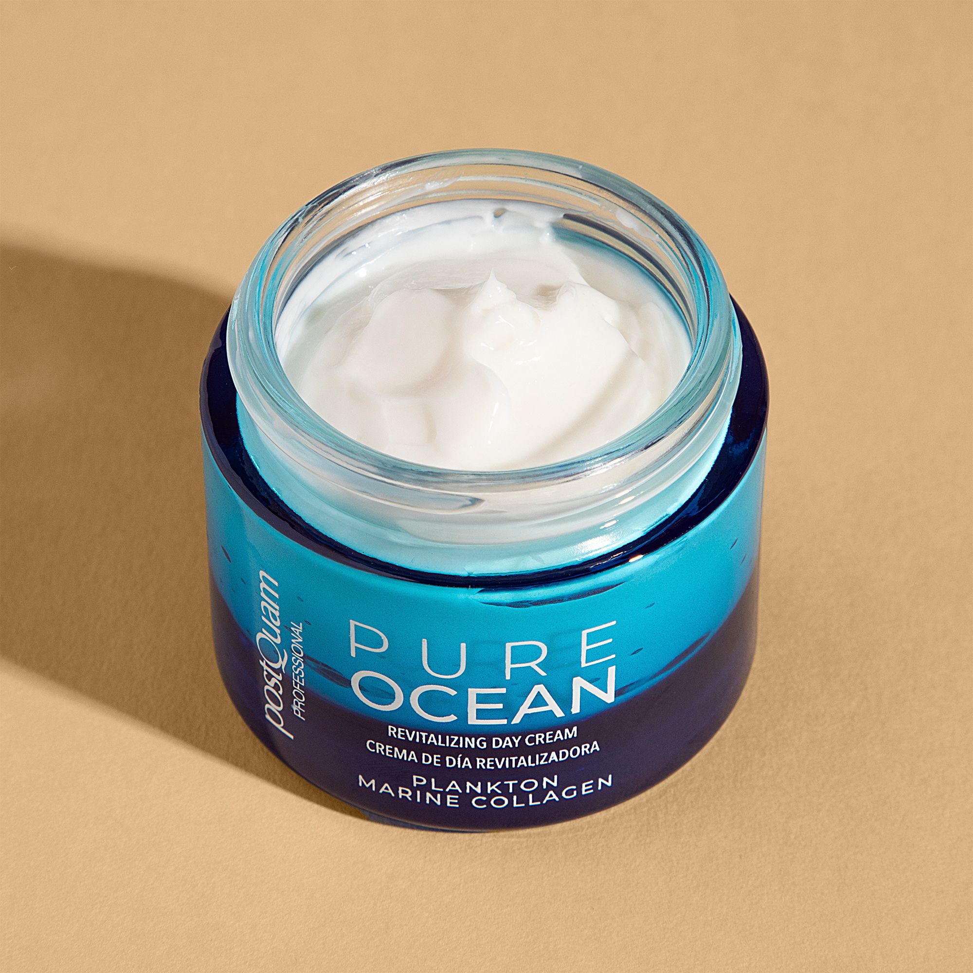 Geöffnete blaue Creme-Dose mit weißer Creme. Aufschrift: PURE OCEAN, Revitalizing Day Cream, Plankton Marine Collagen. Marke: Postquam.