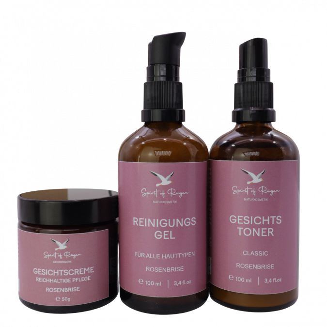 Set mit Gesichtscreme, Reinigungsgel und Gesichtstoner. Braune Flaschen und Tiegel. Rosa Etiketten mit Text.