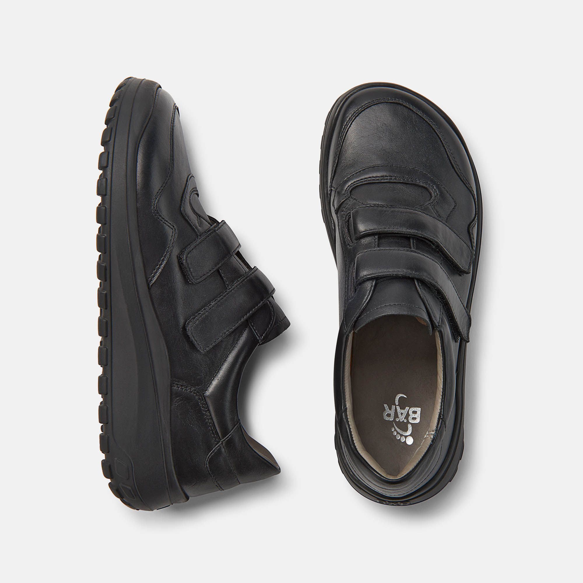 Zwei schwarze Herren-Slipper mit Klettverschluss. Breite Passform. Leder-Obermaterial, dicke Sohle. Draufsicht.