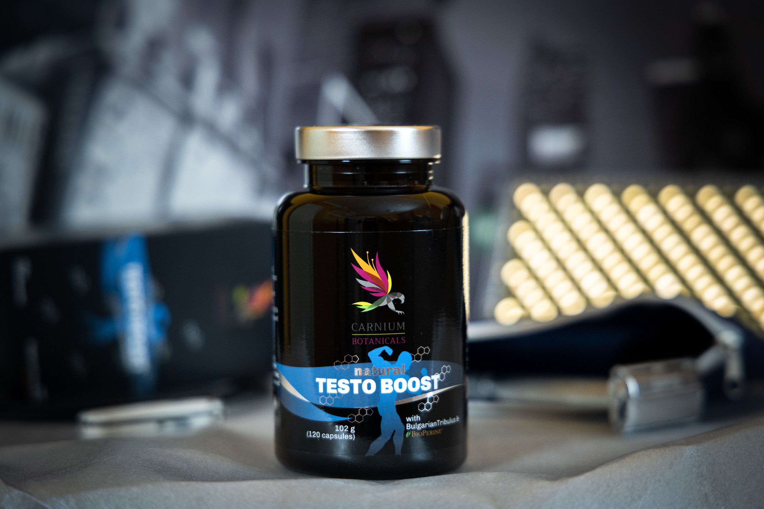 Schwarze Kapsel-Flasche mit silbernem Deckel, auf einem Tisch stehend. Etikett zeigt "Natural Testo Boost".