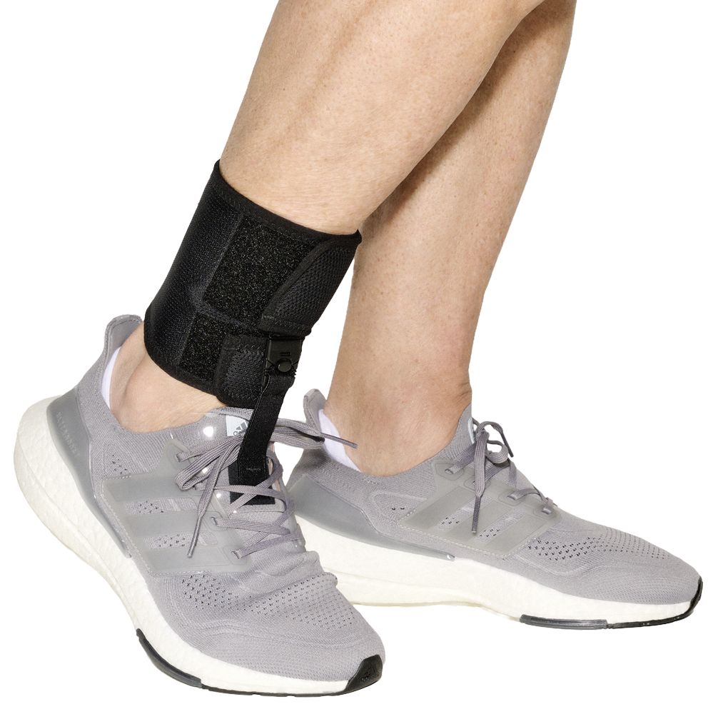 Fußheberorthese mit Schuh an einem Bein, mit grauem Sportschuh.