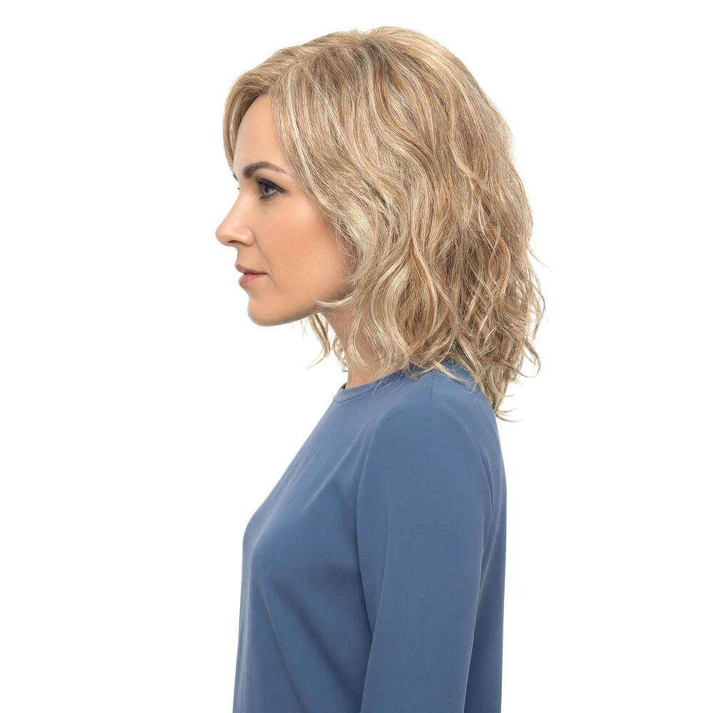 Frau mit blond gewellter Perücke. Seitenansicht. Die Perücke hat blonde und hellbraune Strähnen.