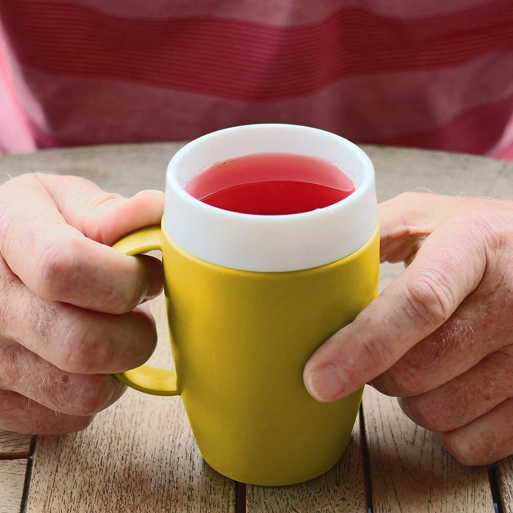 Gelber Becher mit weißem Rand, gefüllt mit roter Flüssigkeit. Hände halten den Becher.