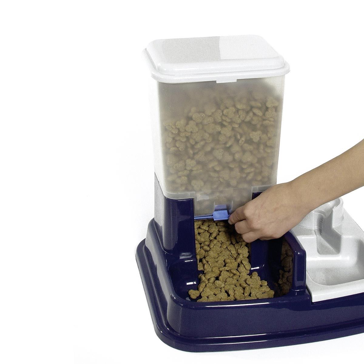 Futterspender mit geöffnetem Ausgabefach. Hand bedient den blauen Schieber. Transparenter Behälter mit Futter.
