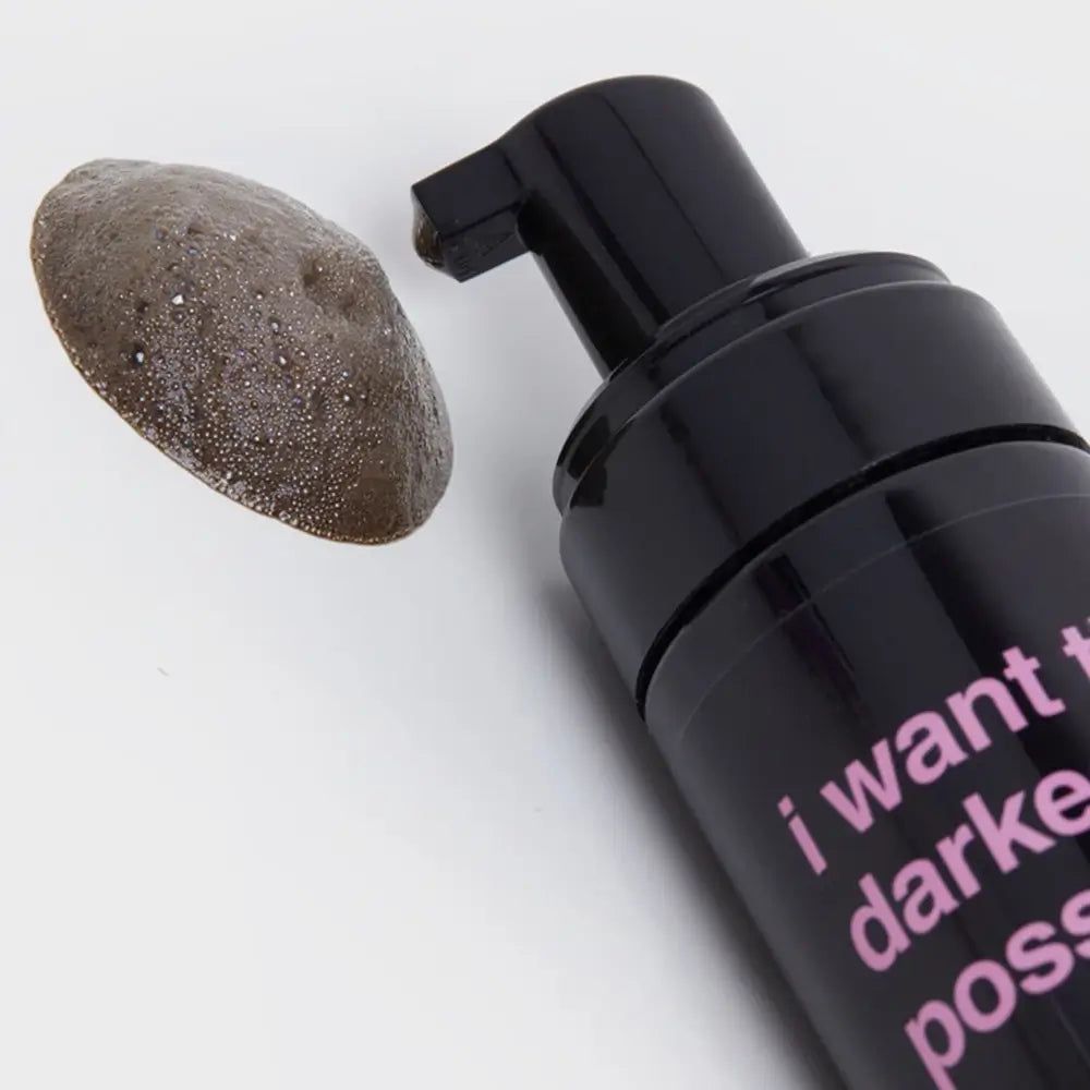 Schwarze Flasche mit Pumpe und gebräunter Schaumprobe. Aufschrift "I want the darkest tan possible".