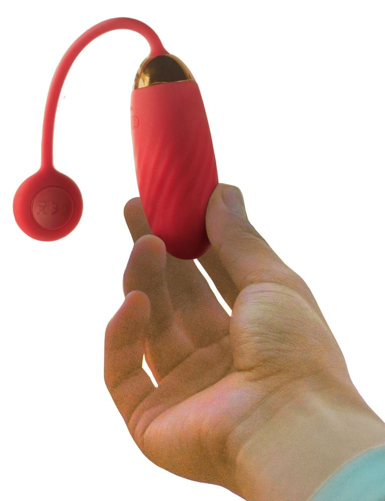 Roter Vibrator mit goldfarbenem Abschluss, gehalten in einer Hand. Rote, runde Basis sichtbar.