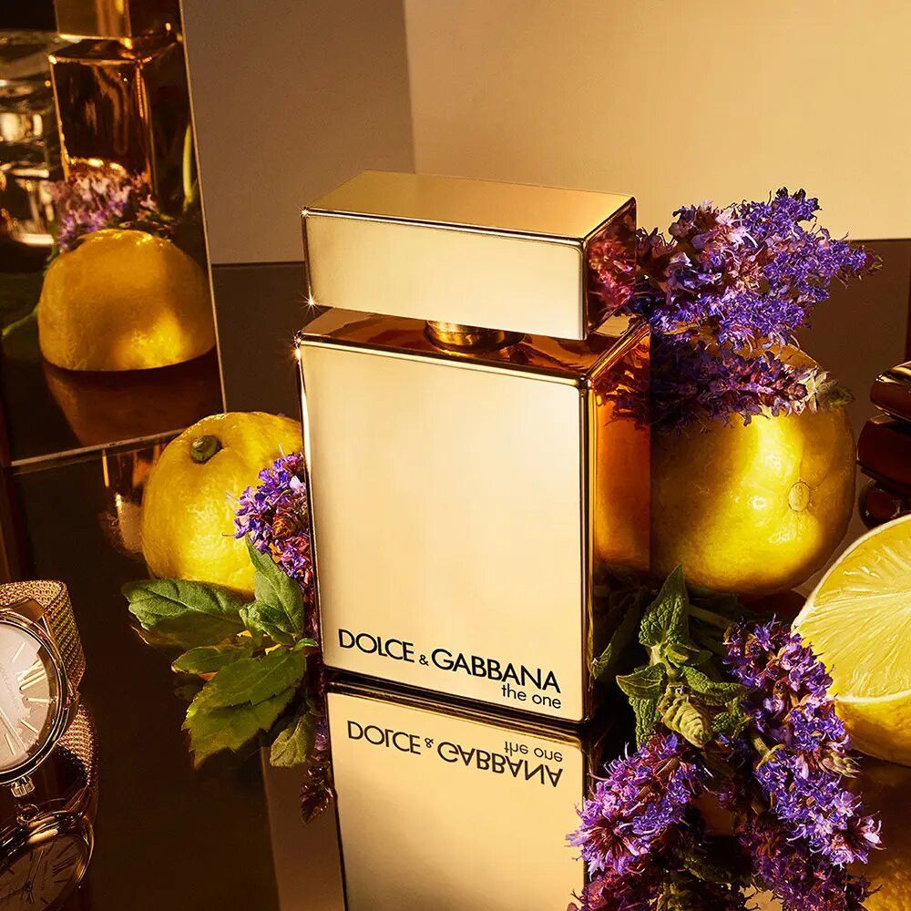 Goldener Flakon, umgeben von Zitronen, Lavendel und einer Uhr. Aufschrift: Dolce & Gabbana the one.