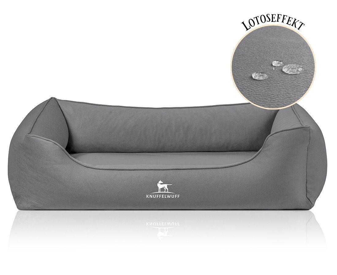 Graues Hundebett mit erhöhtem Rand. Logo: Knuffelwuff. Detail: Wasserabweisender Effekt. Runde Vergrößerung mit Wassertropfen auf der Oberfläche.