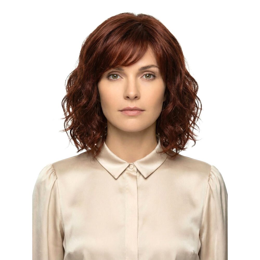 Rote Perücke mit gewelltem Haar und Pony. Frontale Ansicht einer Frau mit hellem Oberteil.