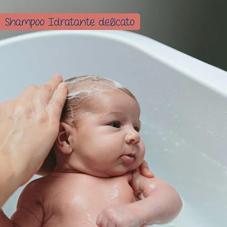 Ein Baby wird in einer Badewanne gewaschen. Eine Hand wäscht das Haar des Babys mit Schaum.