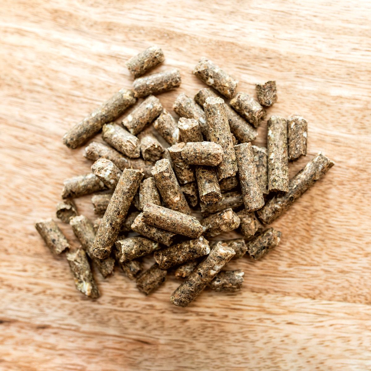 Haufen von zylindrischen Pellets auf Holzoberfläche. Braune Farbe, raue Textur.