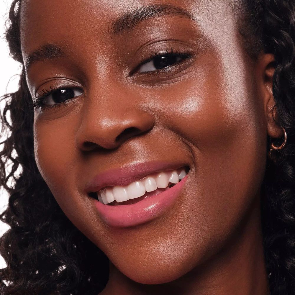 Porträt einer Frau mit rosa Lippenstift. Sie lächelt.