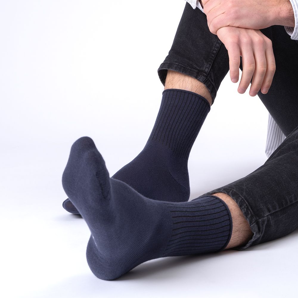 Dunkelblaue Socken ohne Gummibund, die über den Knöchel reichen. Gerippter Schaft.