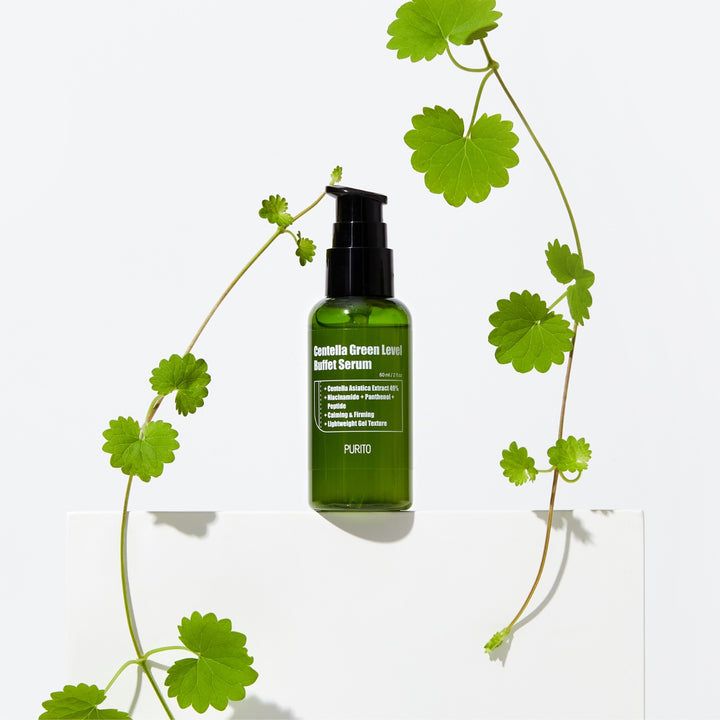 Grüne Flasche mit schwarzem Pumpverschluss, umgeben von grünen Blättern. Beschriftung: Centella Green Level Buffet Serum, PURITO.