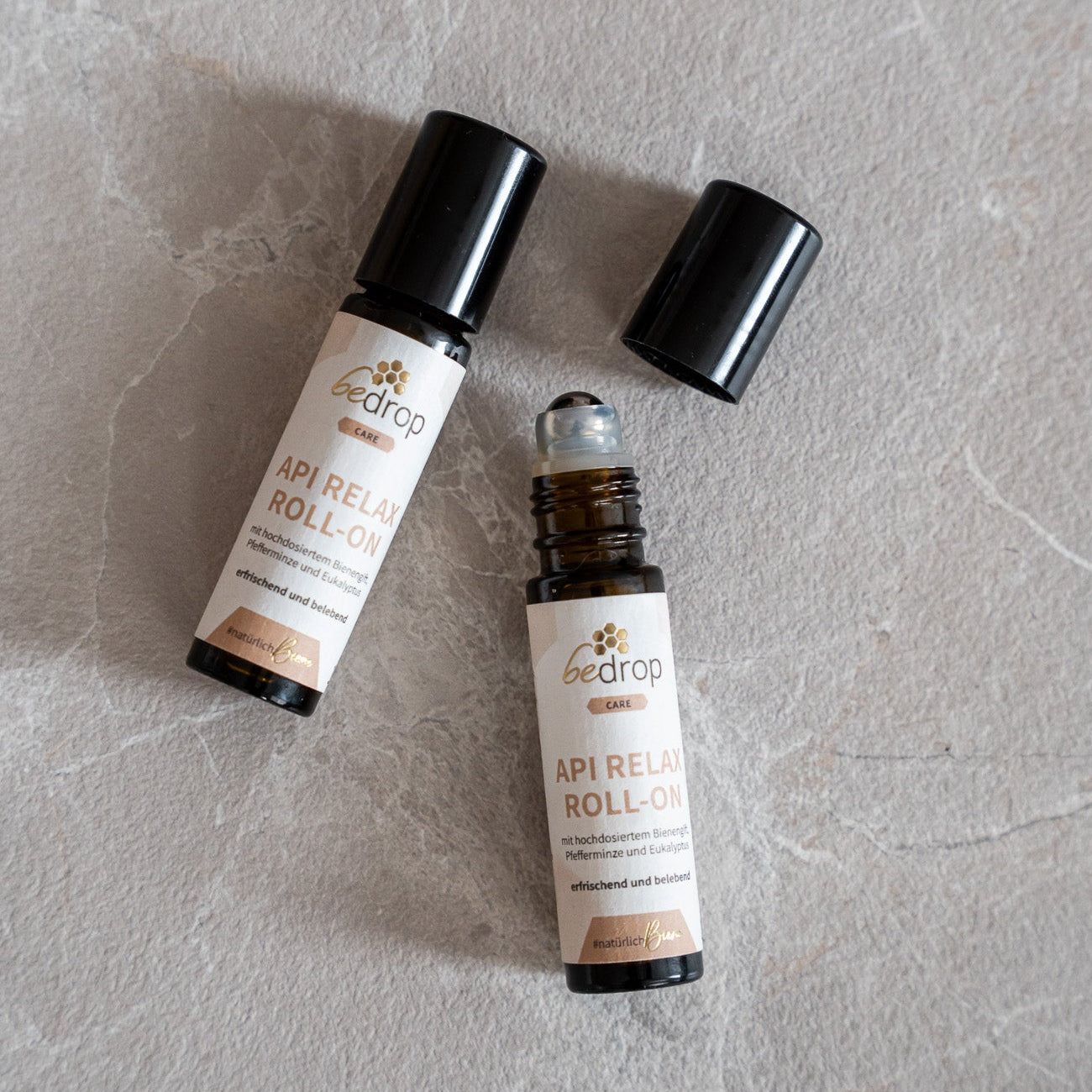 Zwei braune Glasflaschen mit schwarzen Deckeln. Aufschrift: bedrop API RELAX ROLL-ON. Eine Flasche ohne Deckel.