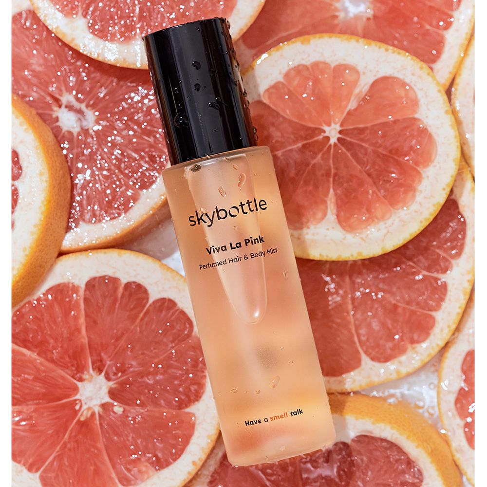 SKYBOTTLE Viva La Pink Hair & Body Mist auf Grapefruit-Hälften. Flasche, Text.