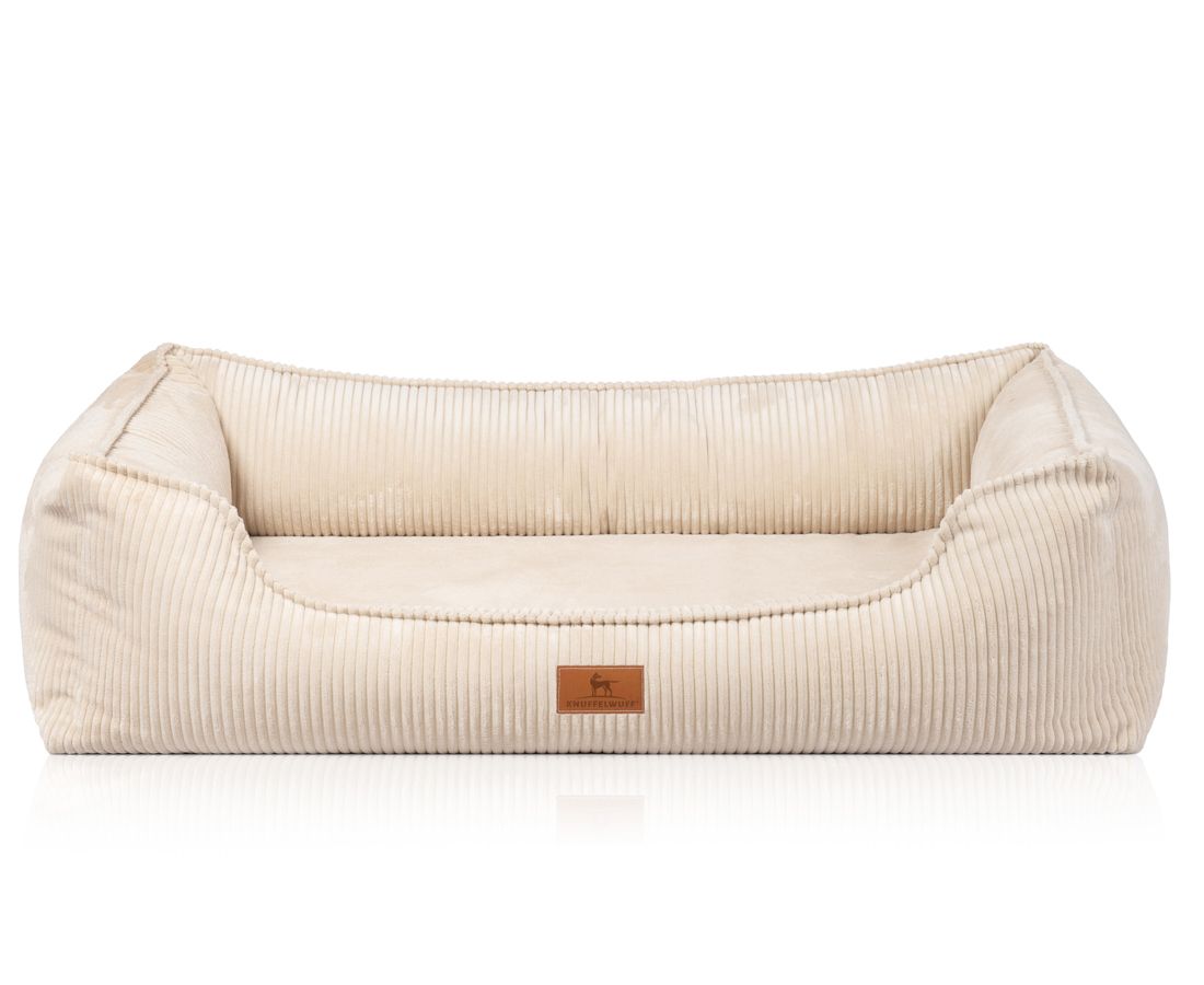 Beiges orthopädisches Hundebett mit Cordstruktur. Rechteckige Form mit erhöhten Seiten. Kleines Markenetikett.