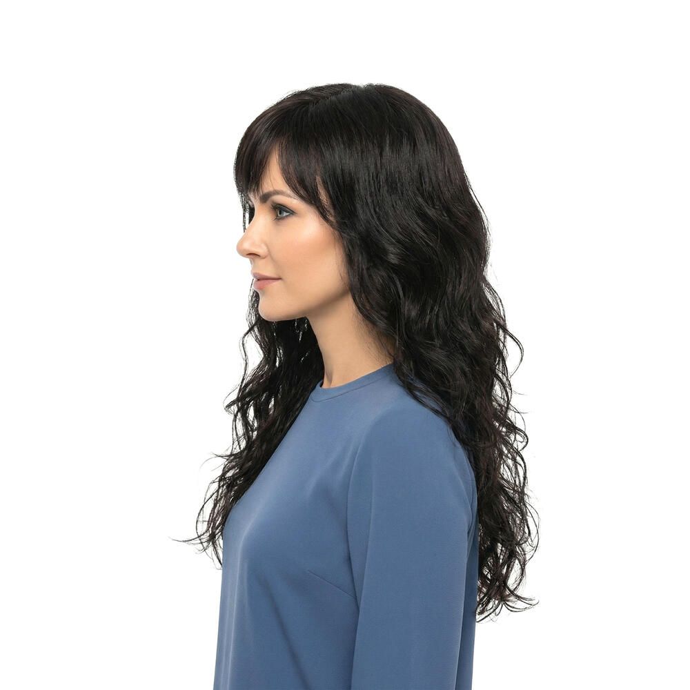 Dunkelbraune Perücke mit gewelltem Haar und Pony. Seitenansicht einer Frau mit blauem Oberteil. Weißer Hintergrund.