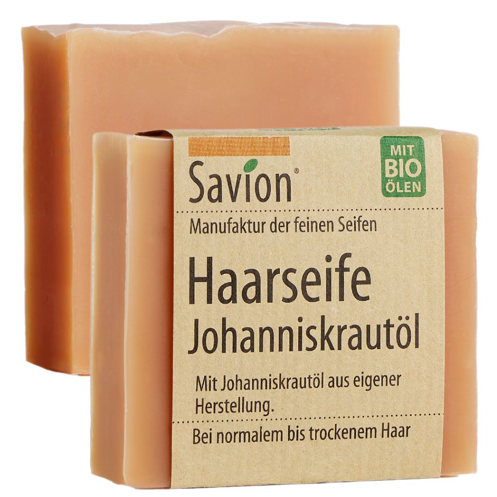 Zwei rechteckige Seifenstücke, eines teilweise verdeckt. Das obere hat eine braune Papierbanderole mit Text: Savion Haarseife Johanniskrautöl. Mit Bio-Ölen.