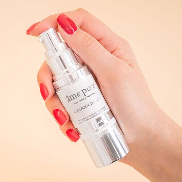 Hand houdt een zilveren fles met witte tekst vast. Productnaam: âme pure Collagen Therapy Gel.