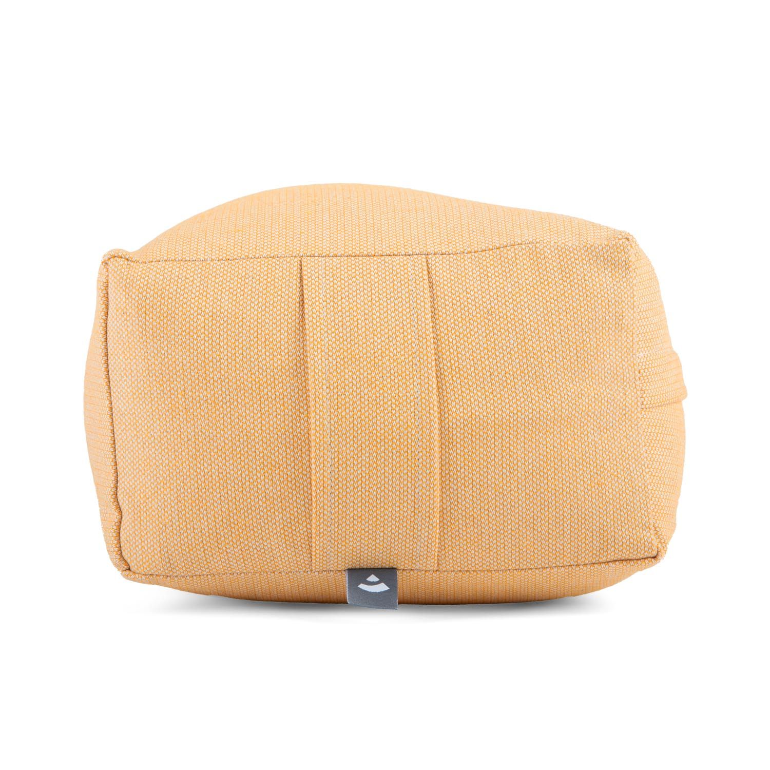 Beige Yoga-Bolster, rechteckig, mit Falten und Logo-Etikett. Stoffstruktur sichtbar.