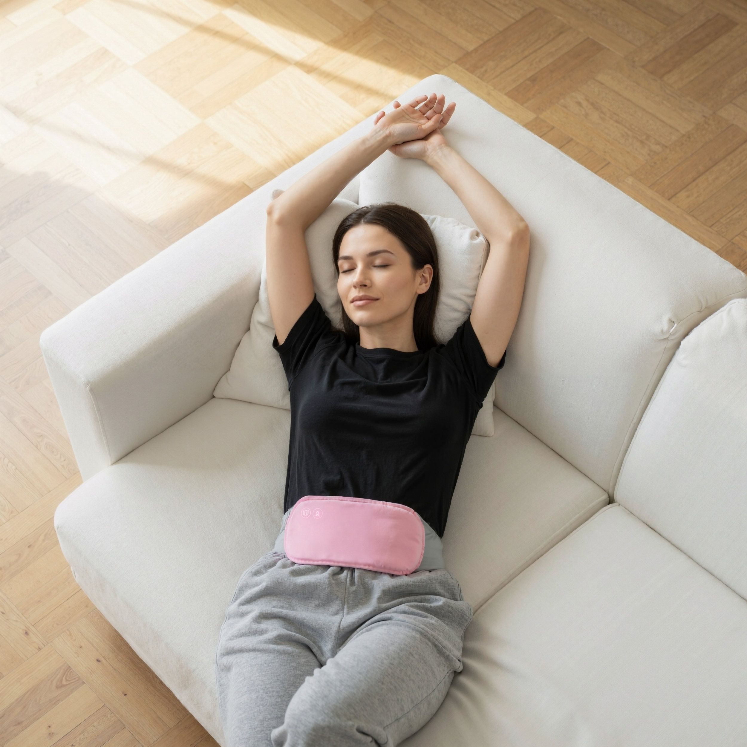 Frau liegt auf einem Sofa, trägt einen rosa Bauchgurt. Der Gurt liegt auf dem Bauch. Arme über dem Kopf.